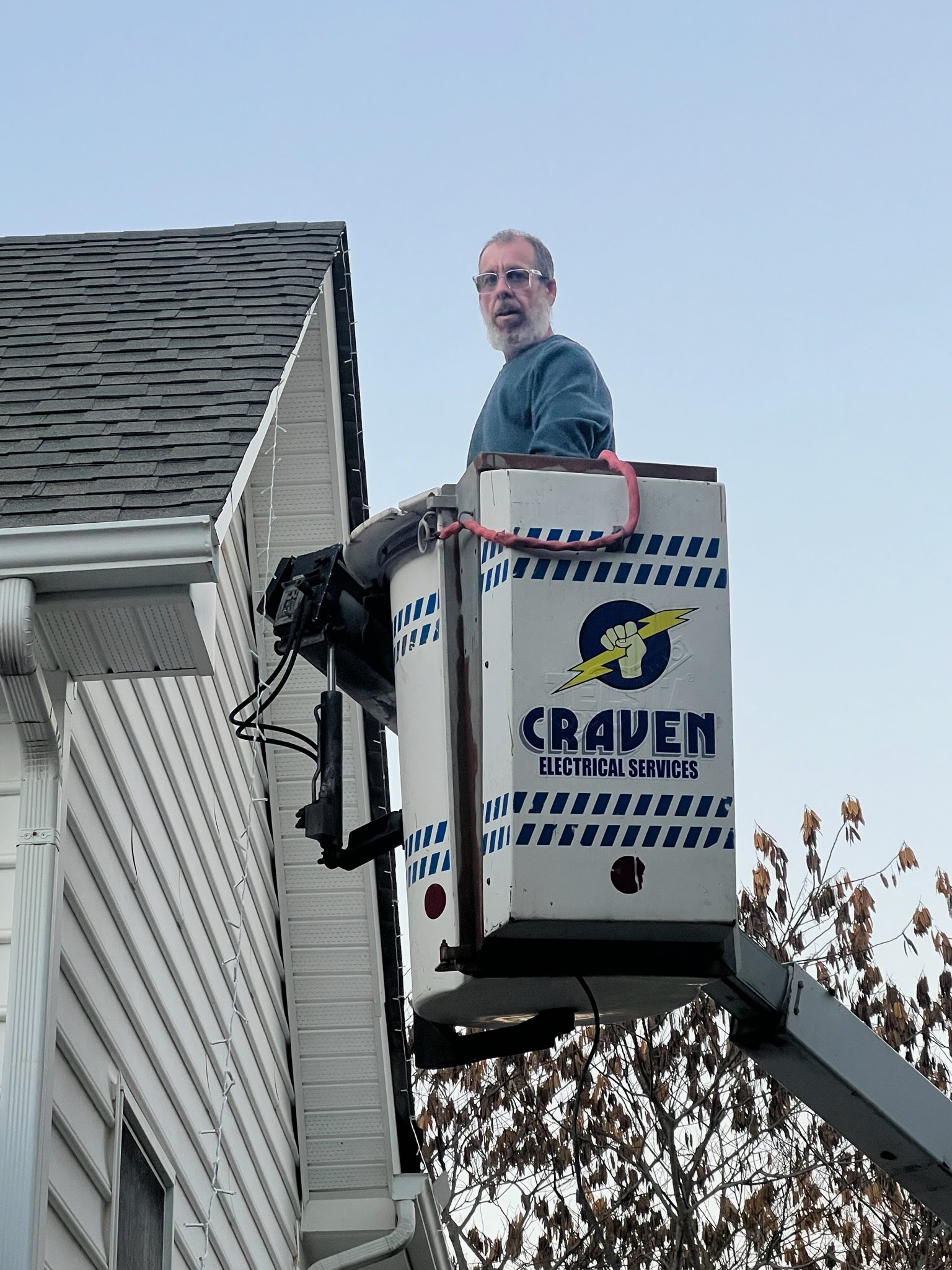 electrical technician in a craven bucket truck installing lights on a home in Virginia.